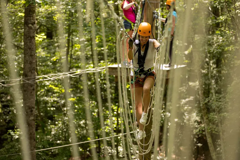 Camper crossing a rope bridge high in the trees