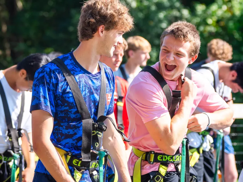 Group laughing together in climbing harnesses before a team building session